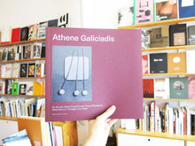 Load image into Gallery viewer, Athene Galiciadis – An Acrylic Brass Pyramid and Three Pendulums Attached to a Triangle on a Table
